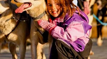 Beito Husky Tours med en liten jente som gir klem til en husky